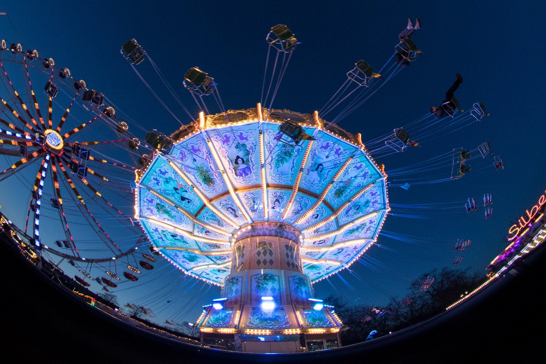 Mit einem Kettenkarussell fiegen Besucher der Dippemess durch die hereinbrechende Dunkelheit. 