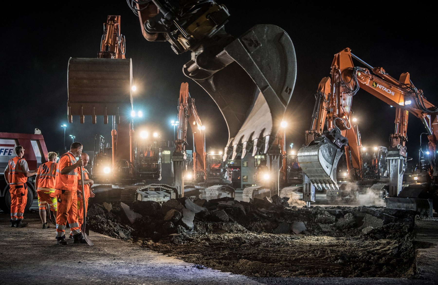Mit Baggern brechen Arbeiter nachts die Asphaltdecke auf dem Vorfeld des Flughafens auf. Foto: Boris Roessler/dpa