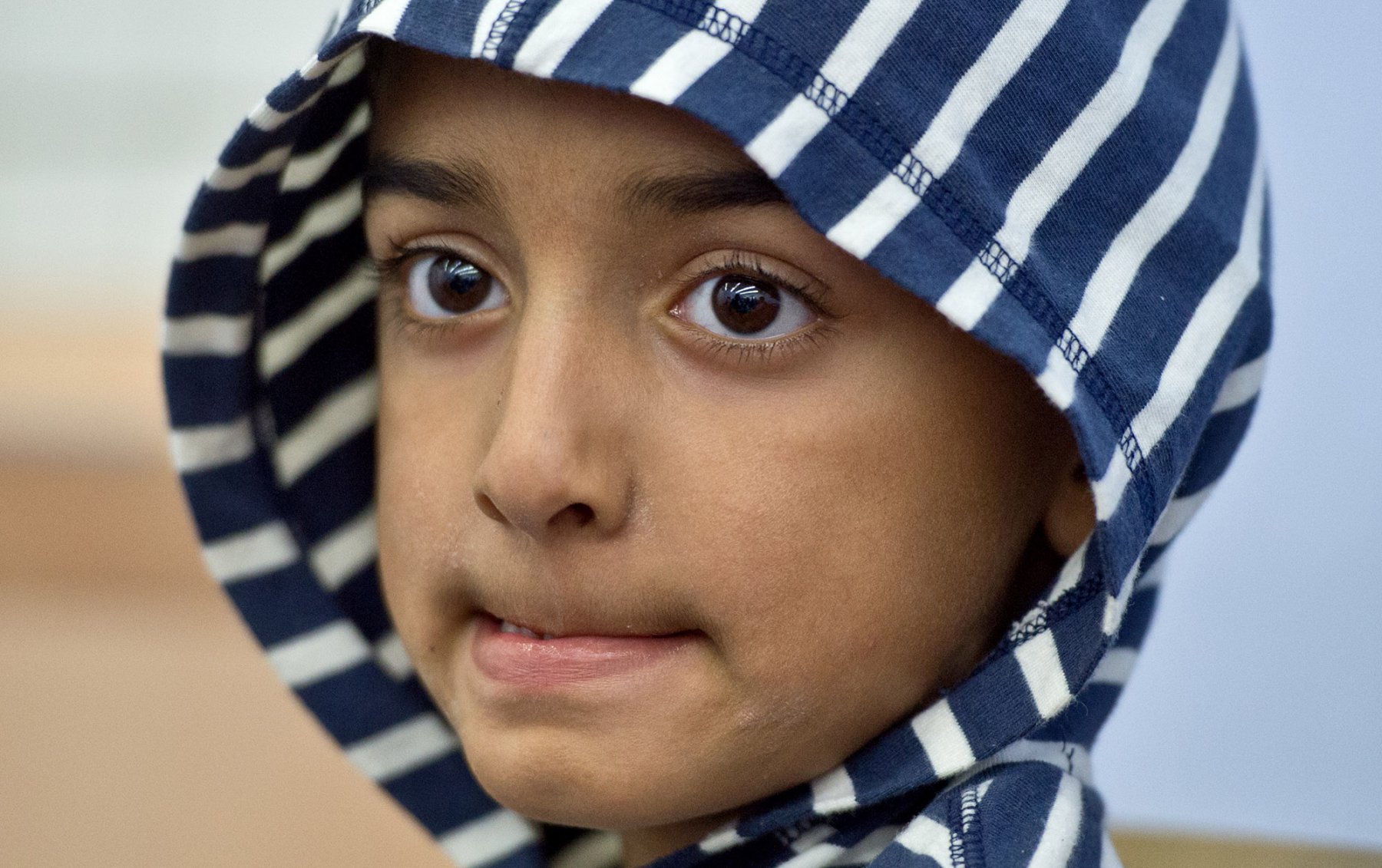 Unterschiedliche Gefühle spiegeln sich im Gesicht des fünfjährigen Maiwand aus Pakistan, während er im improvisierten Befragungsraum der Bundespolizei am Hauptbahnhof in Frankfurt am Main (Hessen) beobachtet, wie seine mit ihm geflohene Mutter von der Polizei befragt wird. Foto: Boris Roessler/dpa 