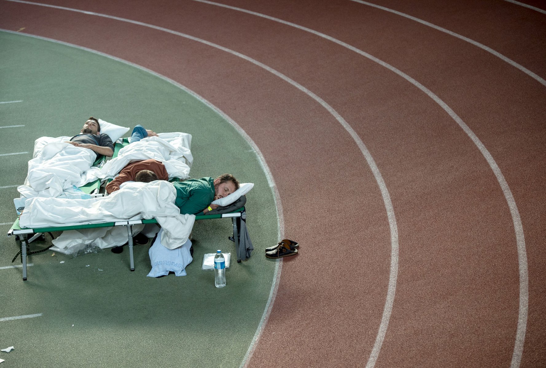 Im Rund der Laufbahn schlafen Flüchtlinge in einer Turnhalle in Hanau auf Feldbetten. Foto: Boris Roessler/dpa