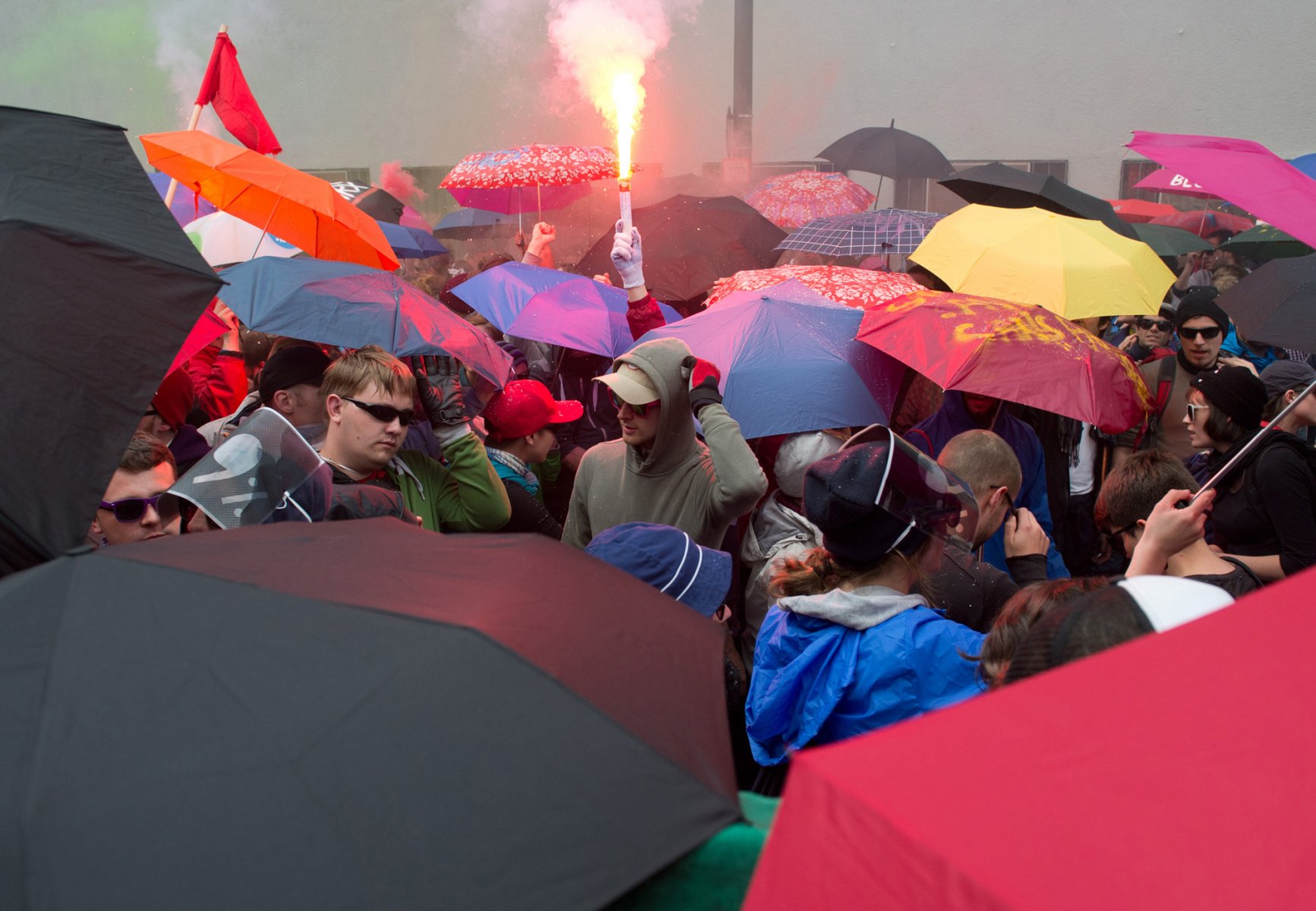 Bengalische Fackeln zünden Demonstranten der Blockupy-Bewegung am 01.06.2013 in der Innenstadt von Frankfurt am Main, während sie von der Polizei eingekesselt sind. Foto: Boris Roessler/dpa