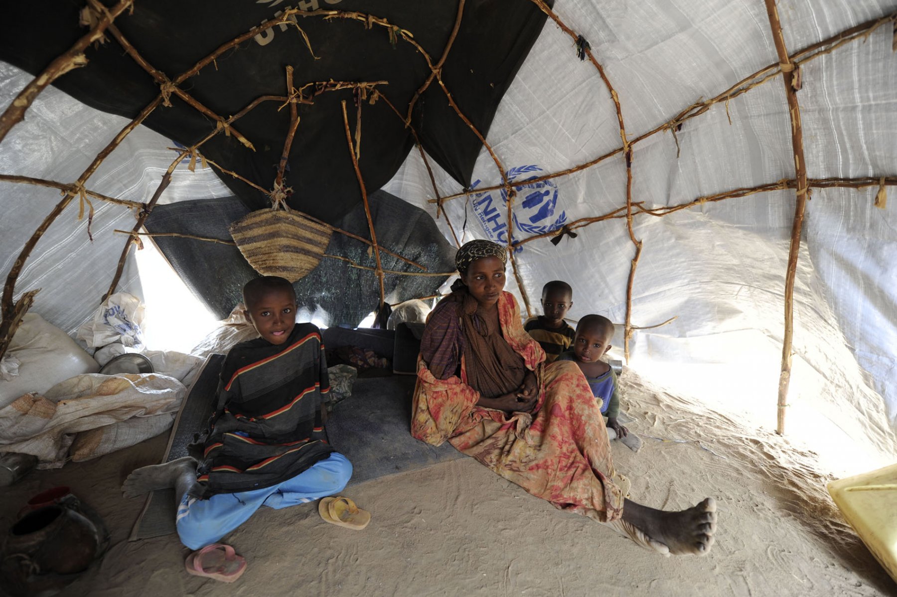 Together with three of her sons and her baby-daughter Salado being hidden undernetah her cloth, 24-year old somalian refugee Habiba Nur sits in her tent in a refugee camp in Dadaab, northeastern Kenya on Tuesday, August 2nd 2011. Since her mother needed two month to make it over the border into Kenya, her daughter was born while the entire family was marching towards the camp. Somalia and parts of Kenya have been struck by one of the worst droughts and famines in six decades, more than 350.000 refugees have found shelter in the worlds biggest refugee camp. Foto: Boris Roessler dpa  +++(c) dpa - Bildfunk+++