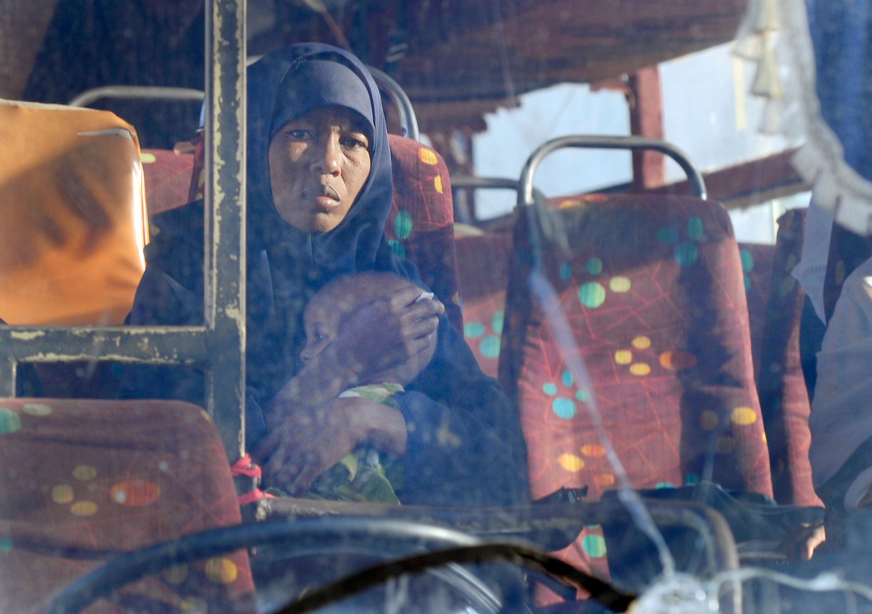 Von der somalischen Grenze kommt ein Bus, in dem eine Frau ihr Kind am Dienstag (02.08.2011) im kenianischen Garissa fest an sich presst. Der sandige Weg durch die Savanne ist der einzige Weg für Hilfskonvois in die Flüchtlingslager im Westen und ist häufig Schauplatz von Überfällen. Kenia ist von einer massiven Dürre betroffen, zehntausende Hungeflüchtlinge aus den Nachbarländern sind in Camps untergebracht. Foto: Boris Roessler dpa