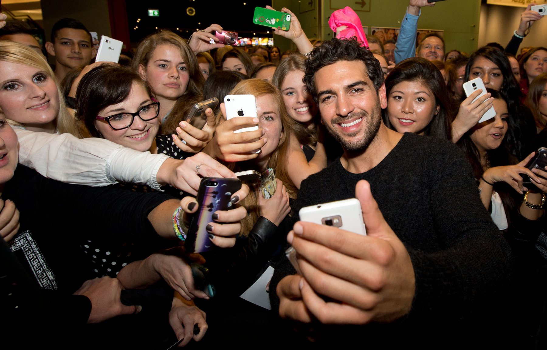 Der Schauspieler Elyas M' Barek posiert vor einem Kinosaal in Frankfurt für Fotos mit seinen weiblichen Fans. Foto: Boris Roessler/dpa 