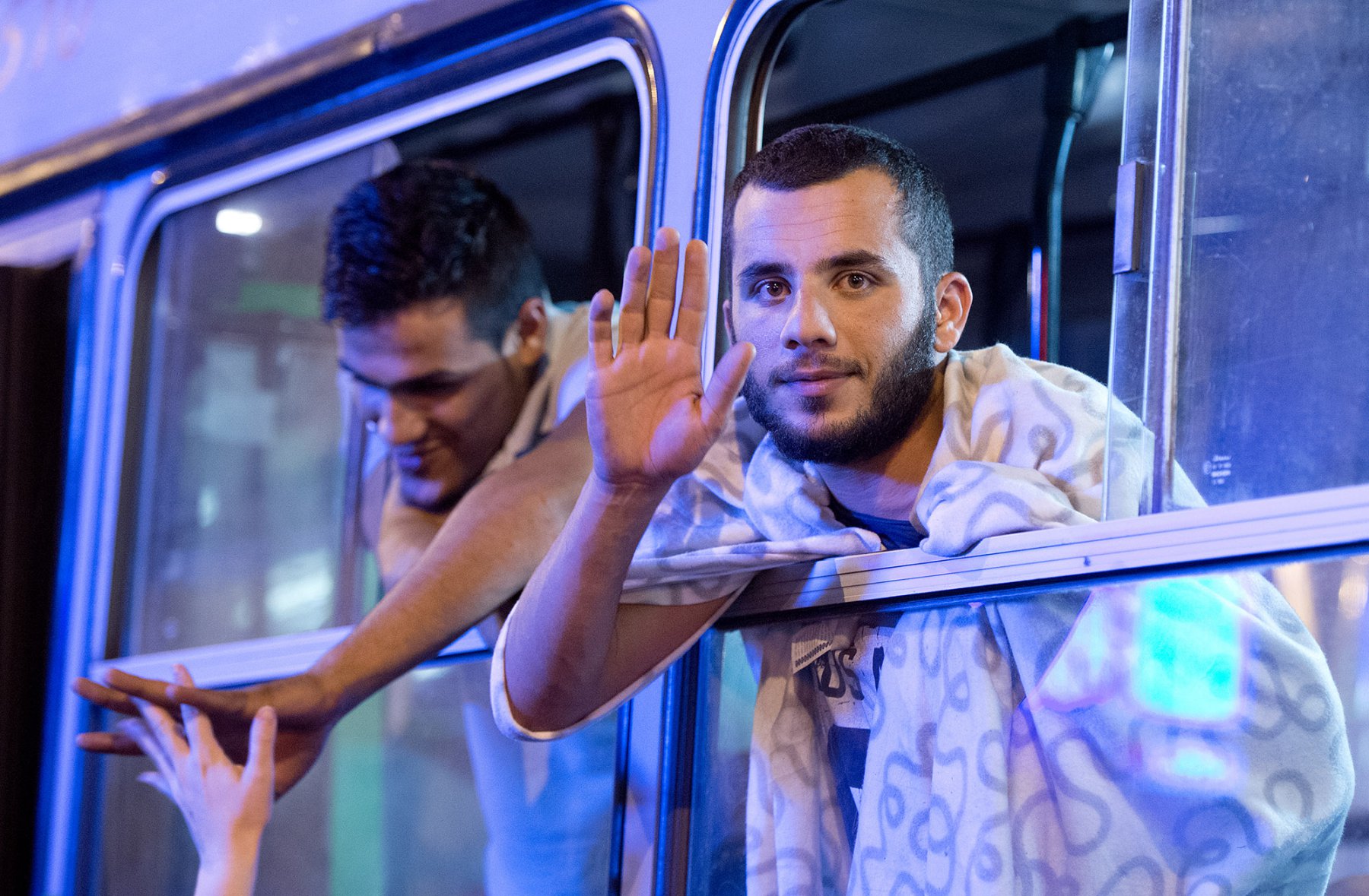 Mitten in der Nacht erreicht tausende Flüchtlinge im am 5. September 2015 vor dem Keleti-Bahmhof in Budapest die Nachricht, dass Sie nach Wochen der Ungewissheit Ungarn verlassen dürfen. Jubelnd steigen die Menschen in bereitgestellte Busse. Foto: Boris Roessler/dpa