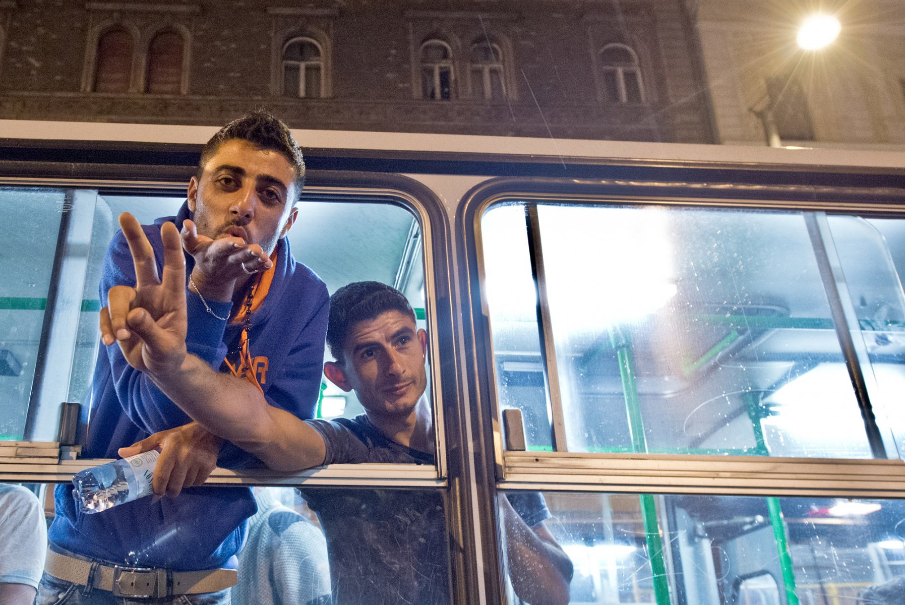 Mitten in der Nacht erreicht tausende Flüchtlinge im am 5. September 2015 vor dem Keleti-Bahmhof in Budapest die Nachricht, dass Sie nach Wochen der Ungewissheit Ungarn verlassen dürfen. Jubelnd steigen die Menschen in bereitgestellte Busse. Foto: Boris Roessler/dpa