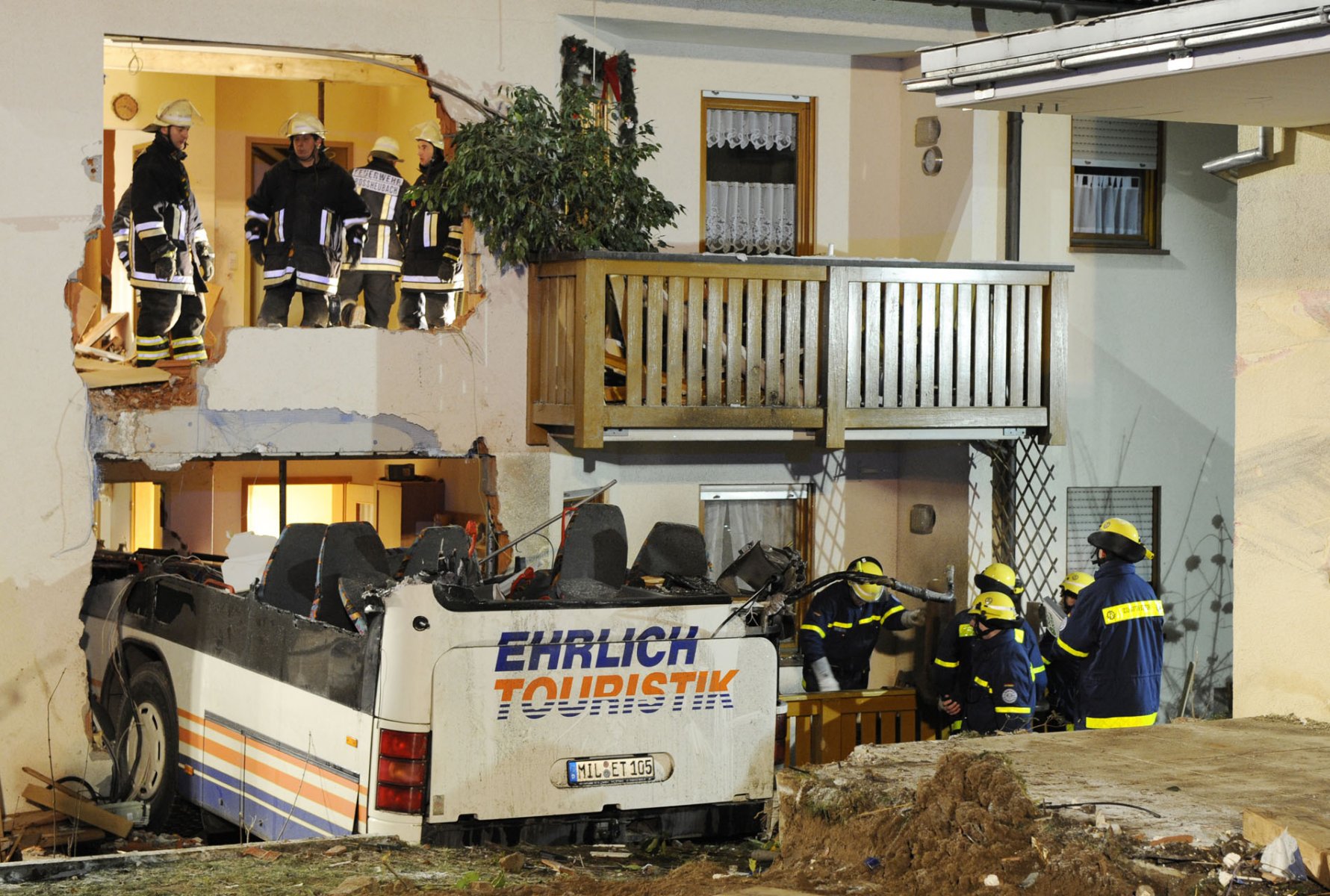 Feuerwehrleute bergen in der Nacht im bayrischen Miltenberg einen völlig zerstörten Linienbus aus einem Mehrfamilienhaus. Foto: Boris Roessler/dpa