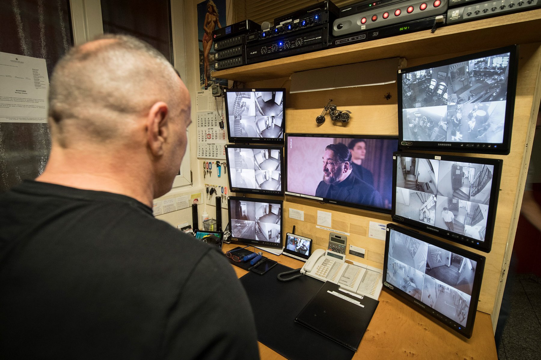 Frankfurt, Bahnhofsviertel, August 2018: Während er nebenbei einen Gangsterfilm schaut, hat der Wirtschafter eines Bordells auf den Überwachungsmonitoren auch die Treppen und Flure des Etablissements im Blick. Foto: Boris Roessler/dpa